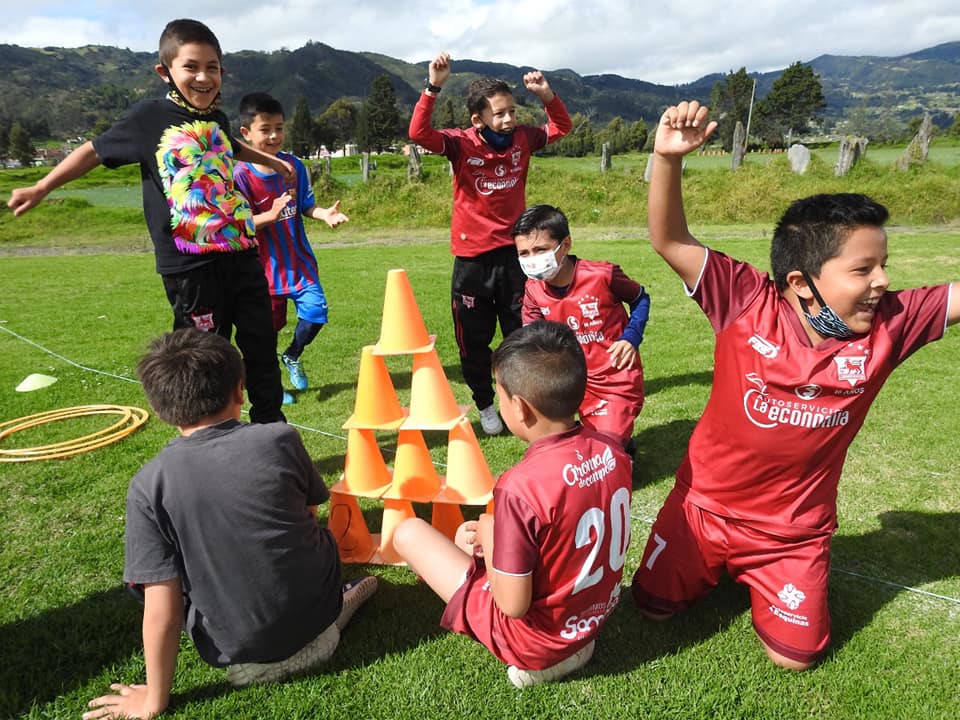 niños jugadores de fútbol haciendo una pirámide con conos, celebrando que no se cayó