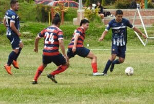 Jóvenes de dos equipos jugando fútbol en una cancha
