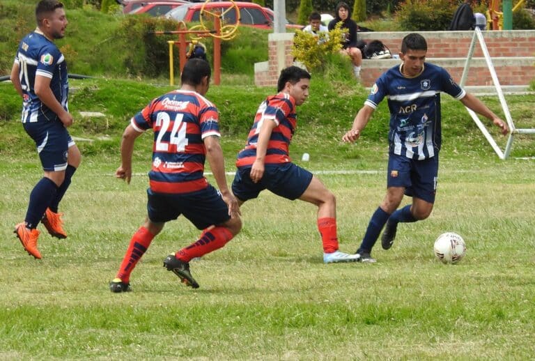 Jóvenes de dos equipos jugando fútbol en una cancha